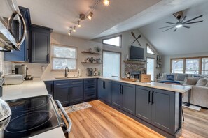 A modern kitchen with dark cabinets, a central island, and a dining area with a black chair.