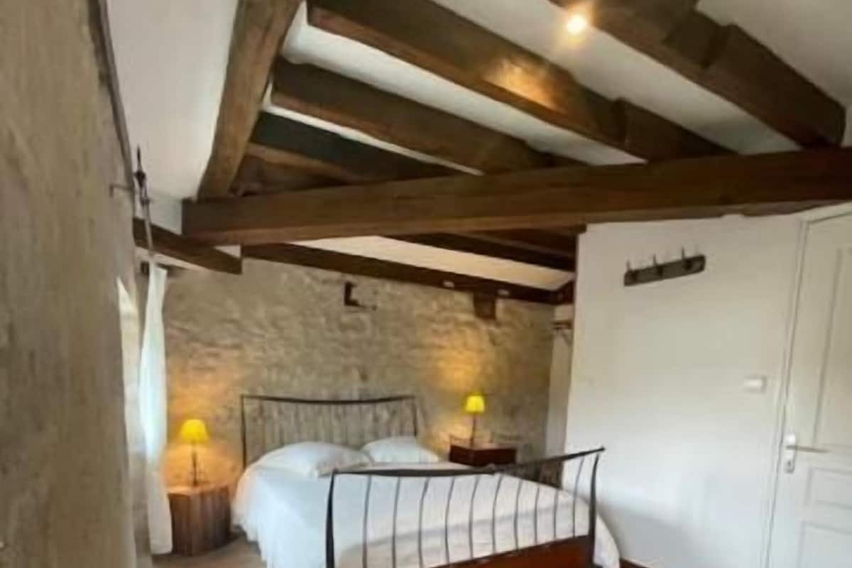 A bedroom with a bed, a nightstand, a lamp, a wardrobe, and a sofa.