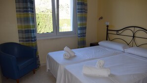 A hotel room with two beds, a blue armchair, and a window with curtains. - Ad1000 in Oliva With 2 Bedrooms and 1 Bathrooms (Oliva)