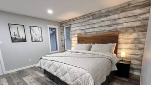 Een slaapkamer met een bed, houten hoofdbord en nachtkastje met lamp.