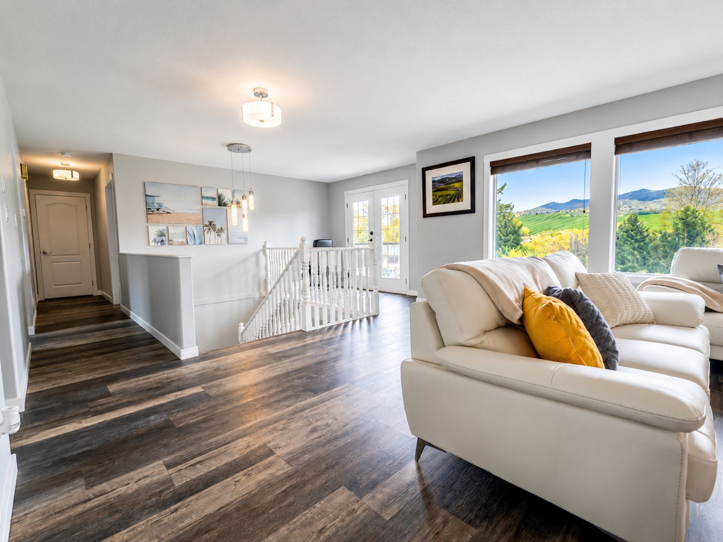 A spacious living area with a white sofa, a staircase, and a view of the outdoors.