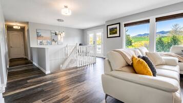 A spacious living area with a white sofa, a staircase, and a view of the outdoors.