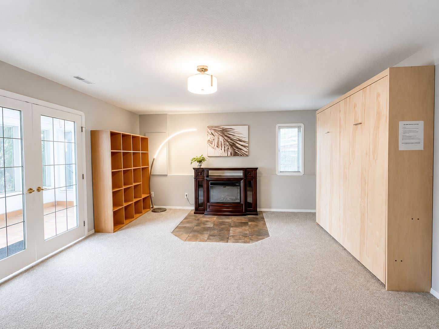A room with a fireplace, a bookshelf, and a large wooden cabinet.