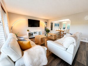 A modern living room with a sofa, coffee table, and a flat-screen TV mounted on the wall. - Spacious Vernon Retreat w/ Game Room, BBQ Patio & Turf Yard (Vernon)