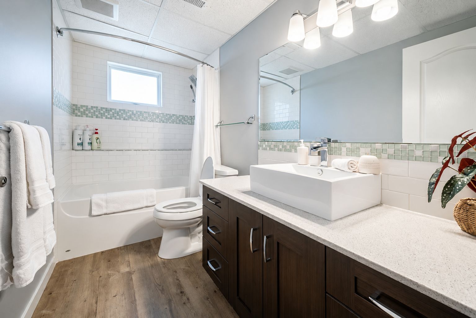 A modern bathroom with a bathtub, toilet, and vanity with a large mirror.