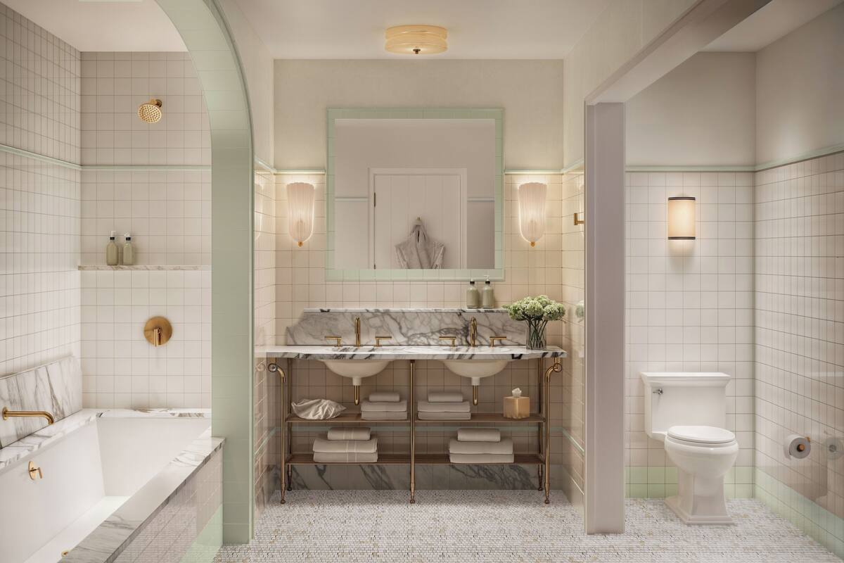 Een badkamer met een bad, een wastafel met een marmeren blad, een toilet en een spiegel met wandlampen.