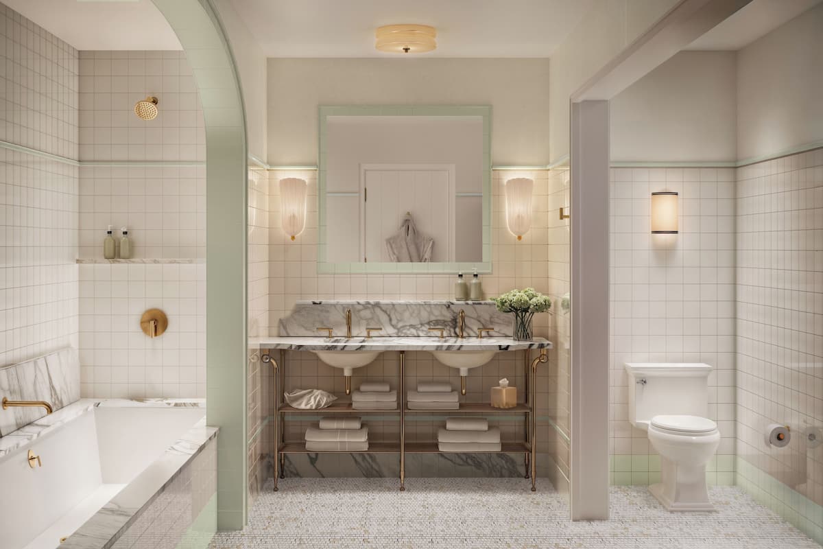 Ein Badezimmer mit einer Badewanne, einem Waschbecken mit Marmorplatte, einer Toilette und einem Spiegel mit Wandleuchten.