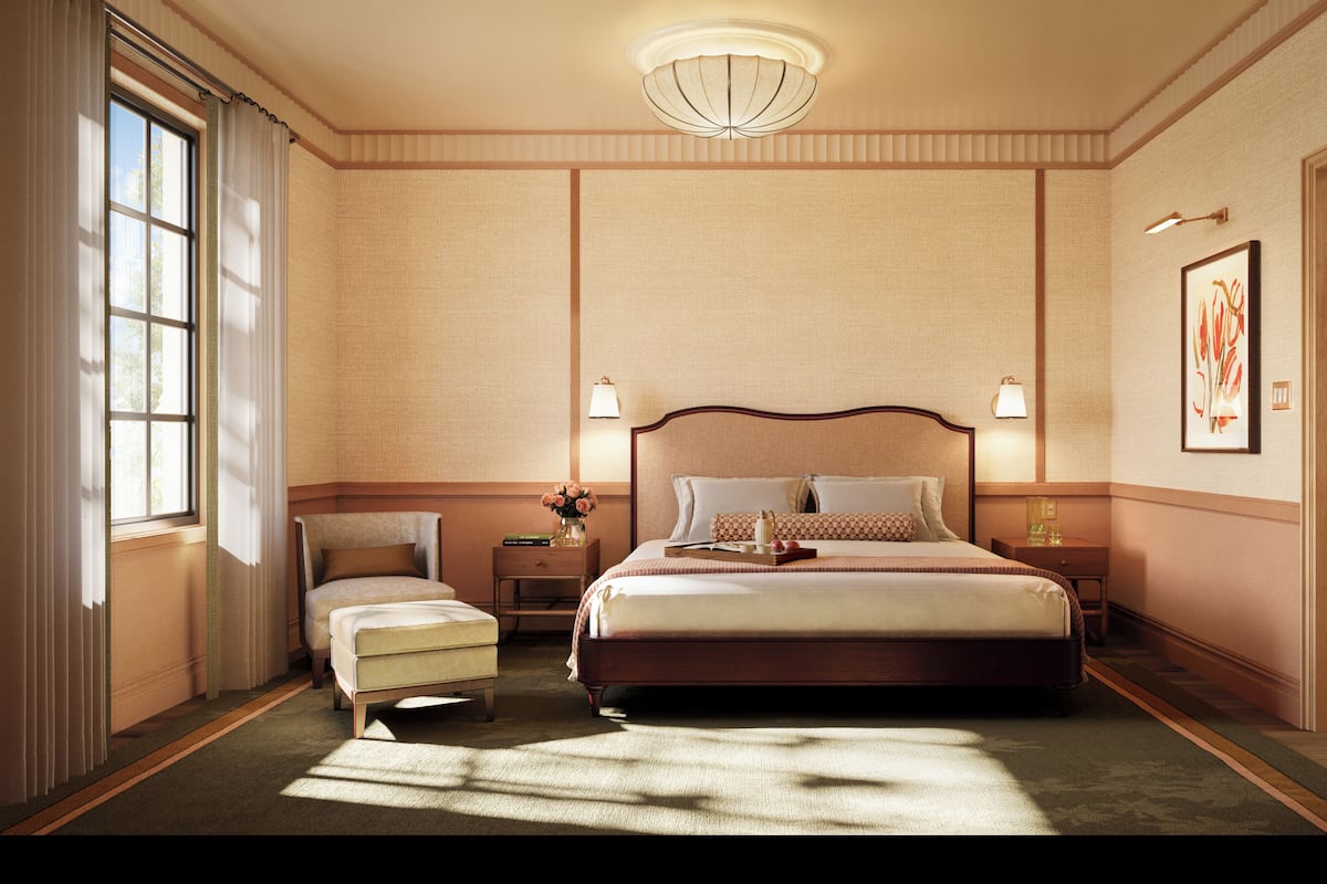 Een hotelkamer met een groot bed, een stoel, een nachtkastje en een raam met gordijnen.