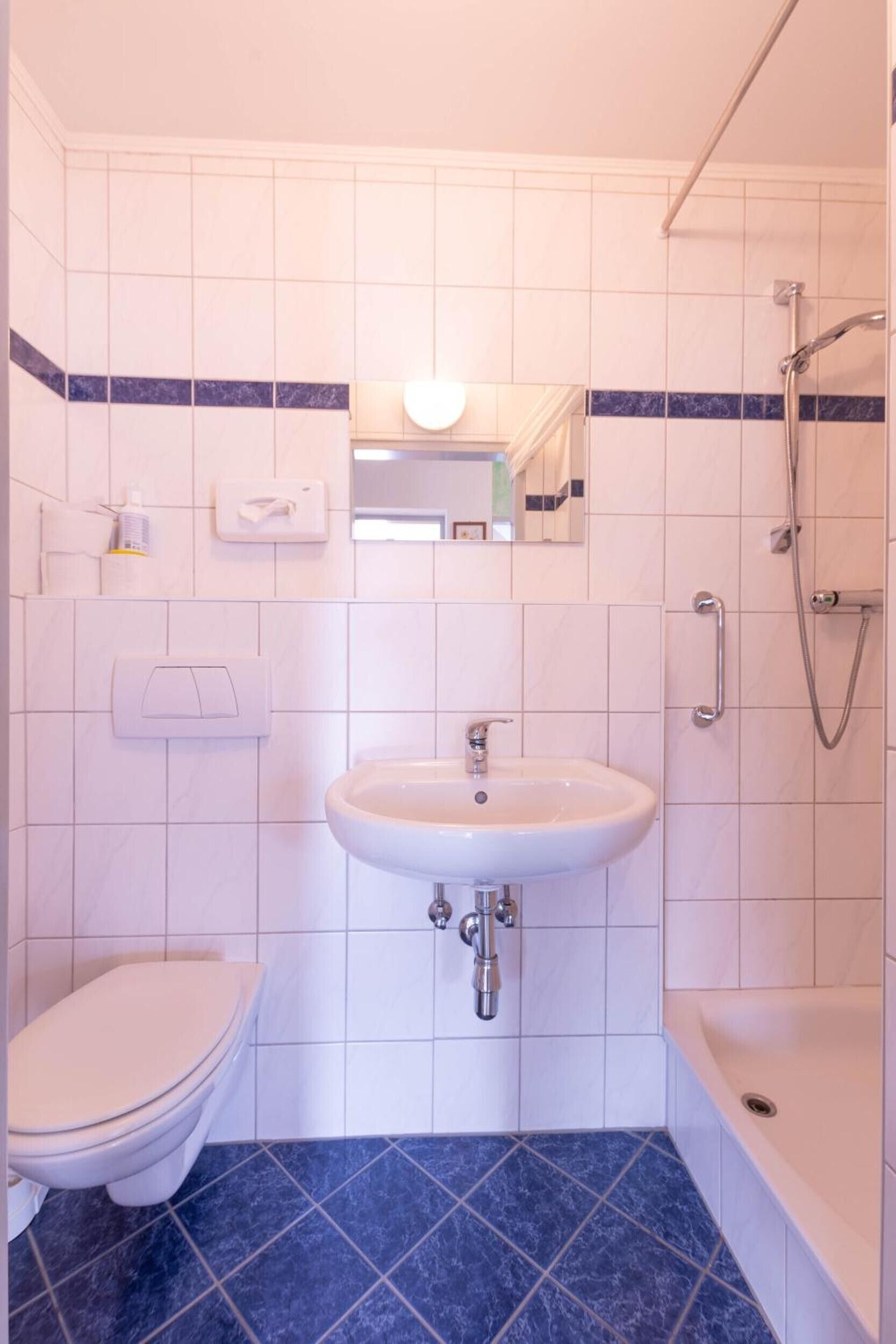 Et badeværelse med toilet, vask og bruser.