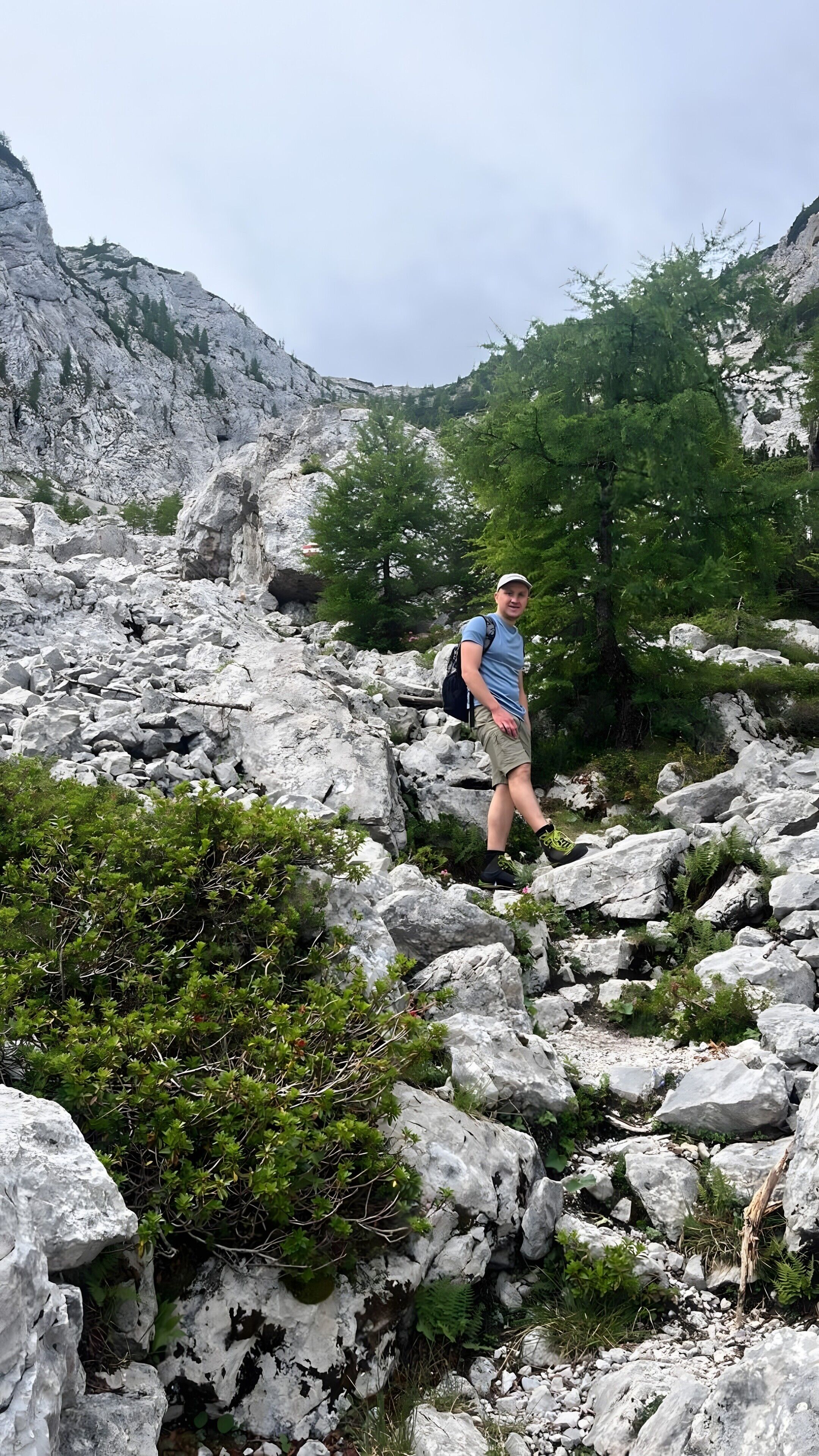 Eine Person wandert über felsiges Gelände mit spärlicher Vegetation.