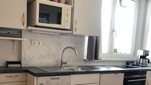 Uma cozinha equipada com lava-louças, pia, janela e máquina de café.