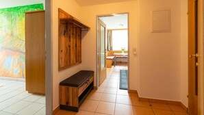 Un pasillo con un banco de madera, un perchero y una puerta que da a una habitación con vistas.