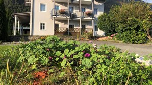 Un edificio de varios pisos con balcones, un acceso cubierto y un jardín en primer plano.