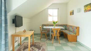 A cozy room with a wooden table, bench, and a television on the wall.