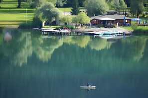 Ein ruhiger See mit einem Steg, Booten und einem Gebäude mit Dach und Fenstern.