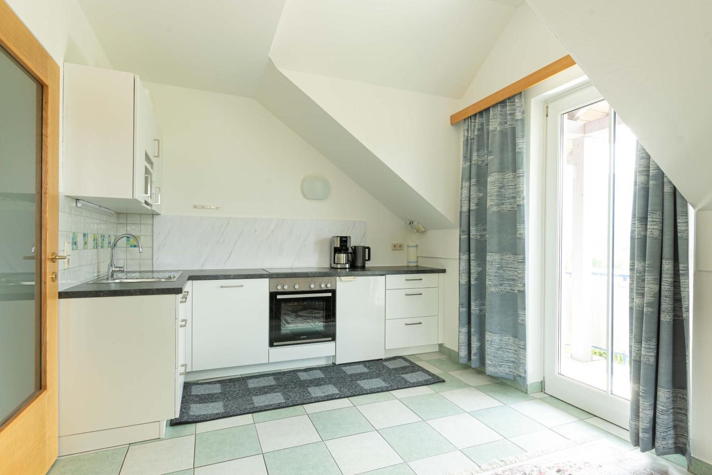 A kitchen with white cabinets, a stove, and a sink.