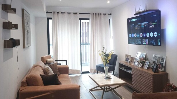 Un salon moderne comprenant un canapé, un fauteuil, une table basse et un téléviseur à écran plat fixé au mur.