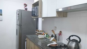 Une cuisine équipée d’un réfrigérateur en acier inoxydable, d’un four à micro-ondes, d’une cuisinière à gaz et d’un meuble en bois au-dessus du plan de travail.