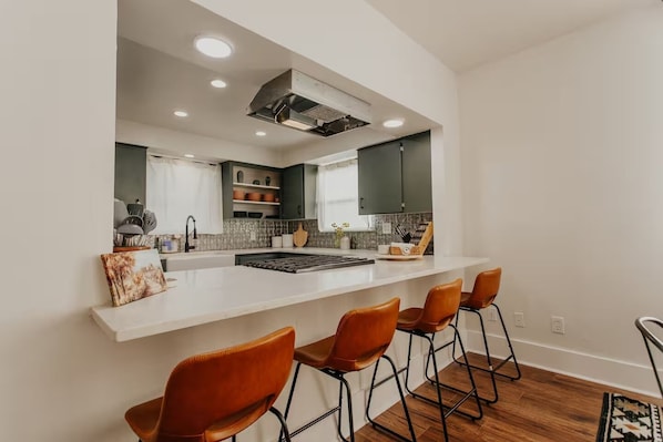 A modern kitchen with a central island, bar stools, and a built-in stove.