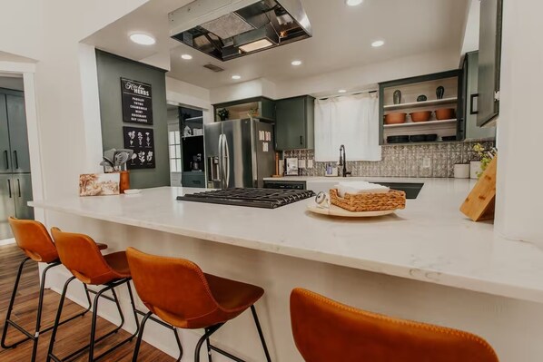 Una cocina moderna con una isla central, taburetes de bar y un refrigerador empotrado.