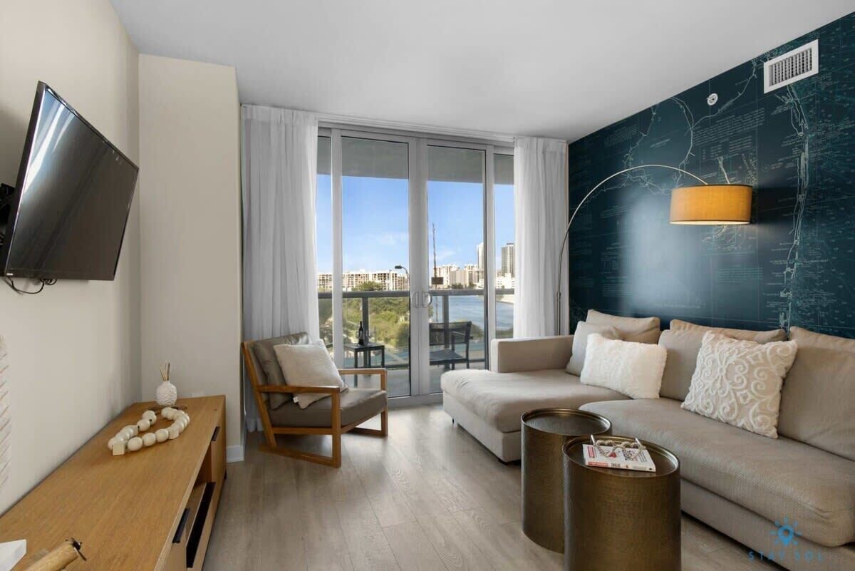 Uma sala de estar moderna com sofá, poltrona, mesa de centro e televisão.