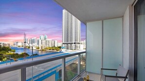 A balcony with a view of a cityscape, including a tall building and a bridge. - Relax Above It All | Hallandale Condo w/ Balcony (Hallandale Beach)