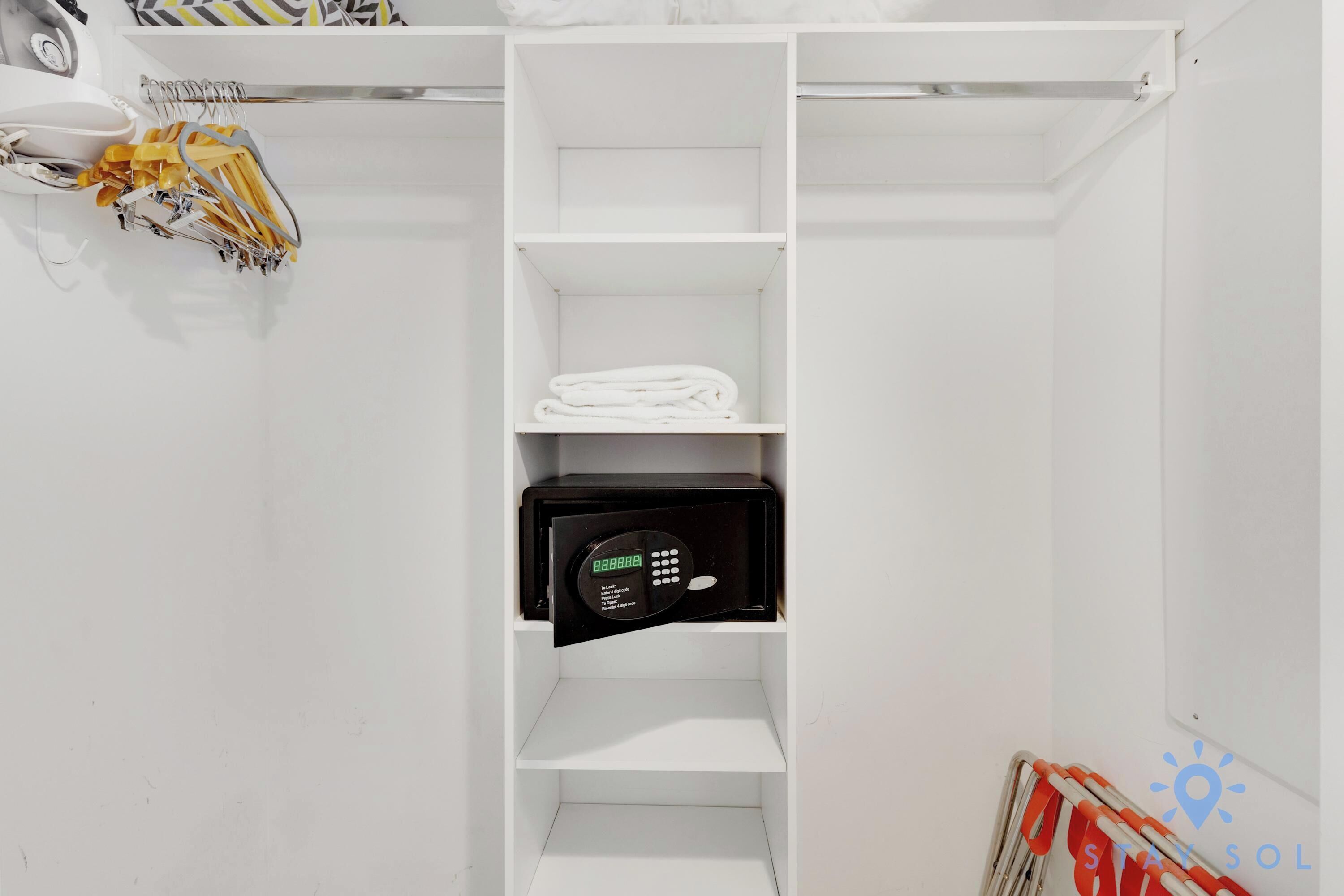 A white closet with shelves, a hanging rack, and a microwave.