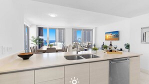 A modern kitchen with a large island, a dining area with a view, and a built-in dishwasher. - Beautiful Apt w/ Private Balcony + Incredible Pool (Hallandale Beach)