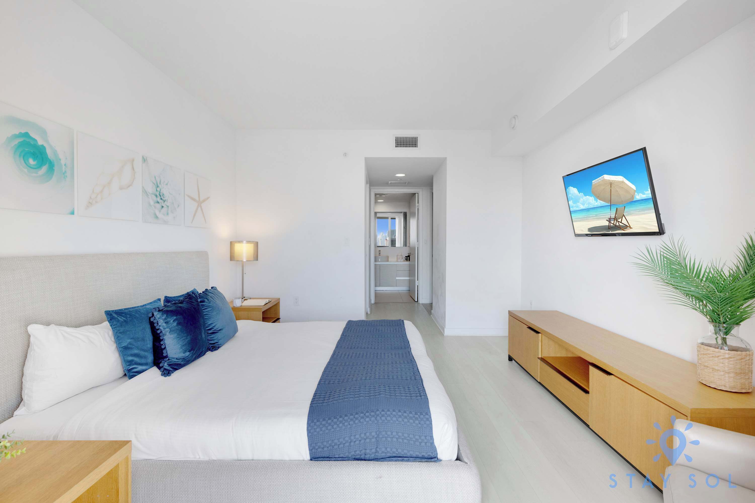Habitació d'hotel moderna amb un llit gran, una taula de consola de fusta, televisió penjada a la paret i vista al passadís.