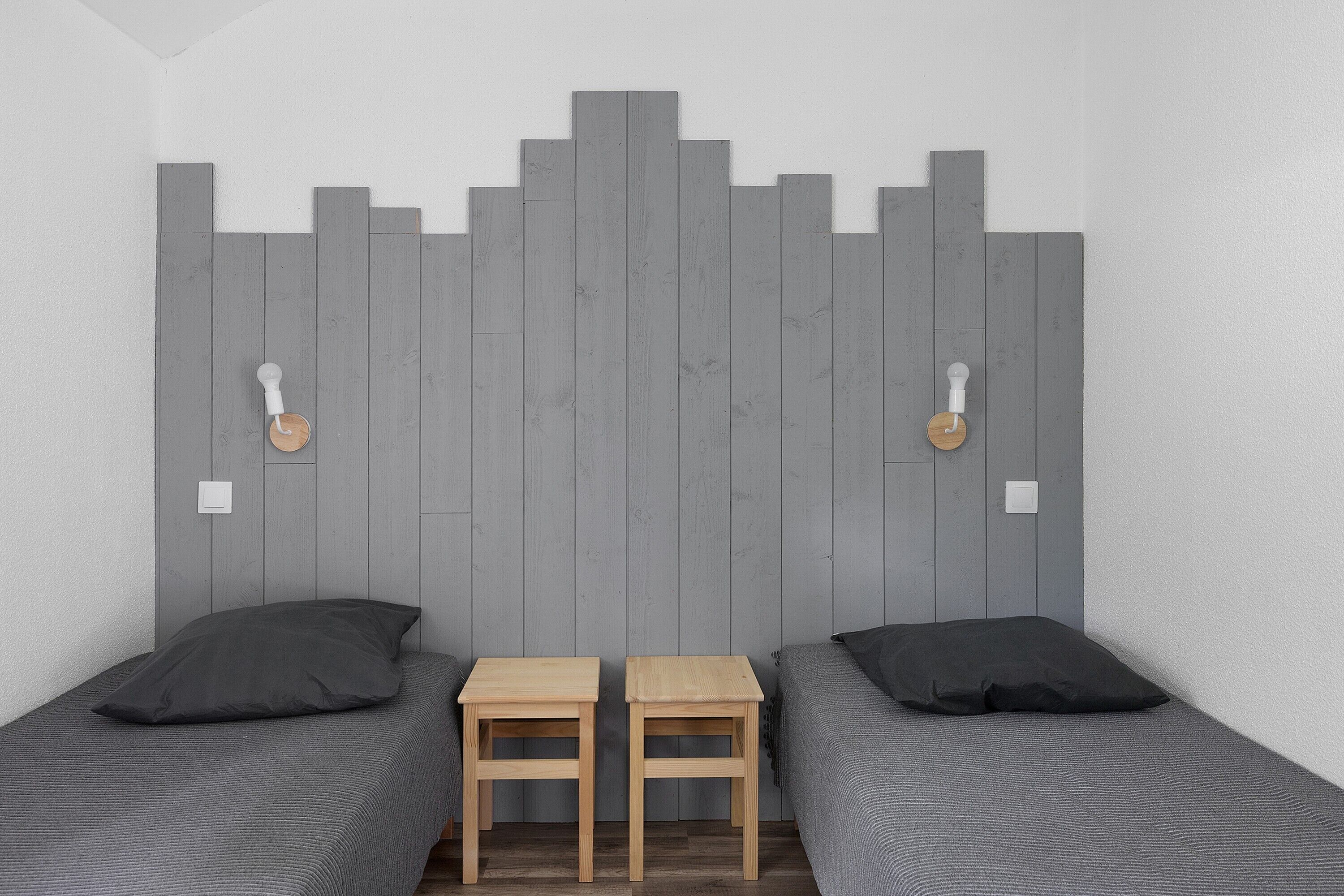 Een kamer met twee bedden, een houten hoofdeinde en twee tafeltjes.