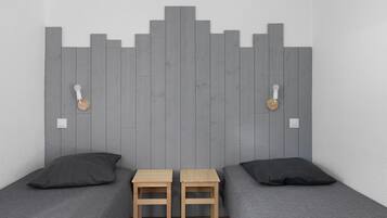 Een kamer met twee bedden, een houten hoofdeinde en twee tafeltjes.