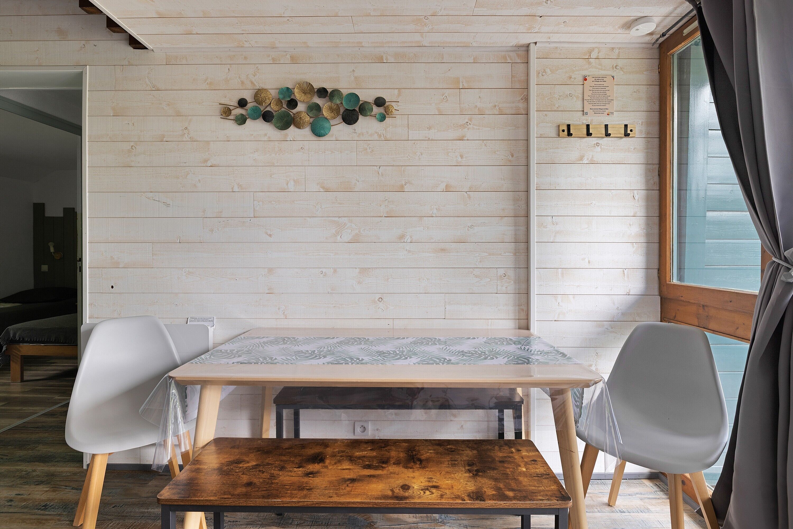 A wooden-paneled room with a table, chairs, and a decorative wall piece.