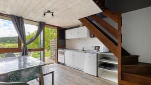 Eine moderne Küche mit weißen Schränken, einer Holztreppe und einem Essbereich mit Tisch und Stühlen.