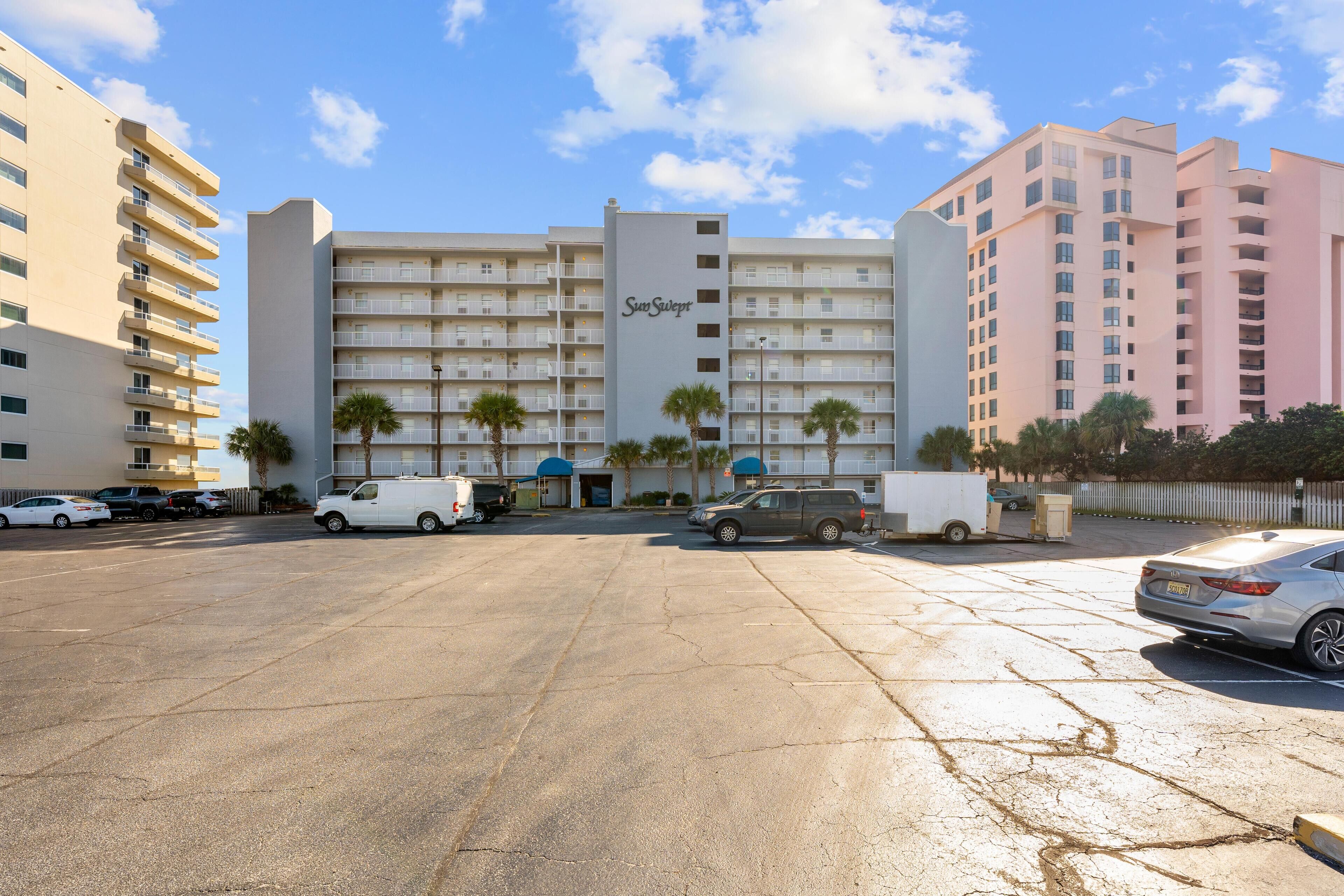 Ein Hotel mit mehreren Stockwerken, einem Parkplatz und einigen Fahrzeugen.
