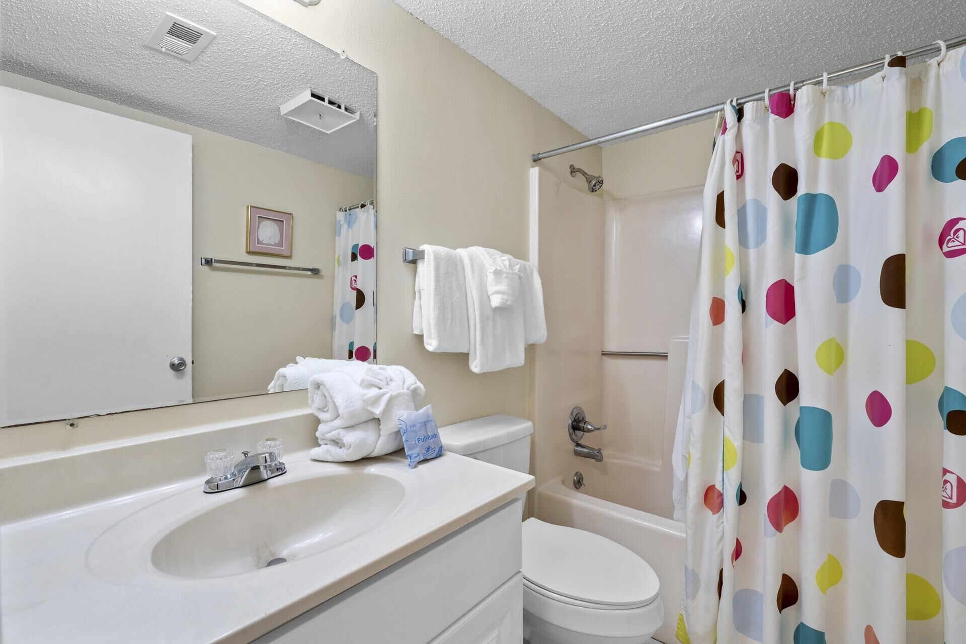 A bathroom with a sink, toilet, shower, and a mirror.