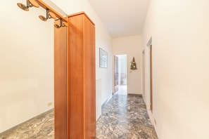 Ein Korridor mit einer Holztür, einem Marmorboden und einem gerahmten Bild an der Wand.