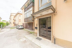 Eine enge Straße mit einem geparkten Auto und einem Gebäude mit einem Balkon.