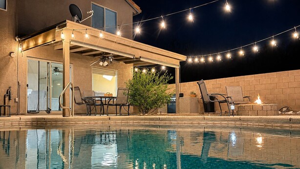 A poolside area with a covered patio, outdoor furniture, and string lights. - Your Cozy Desert Retreat – Pool • Fire Pit • Convenient Location (Green Valley)