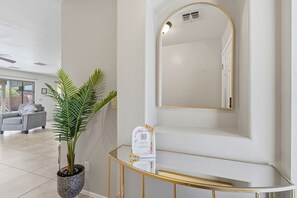 Un intérieur moderne agrémenté d’une plante en pot, d’une console en verre et d’un grand miroir.