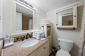 Een badkamer met een wastafel, spiegel, handdoekhouder en toilet.