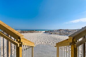 A wooden staircase leading to a sandy beach with a clear sky. - Sunrise Village 111 (Gulf Shores)