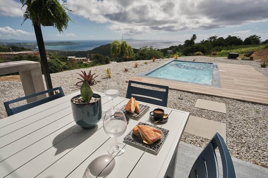 A dining table with a view of a pool and landscape.