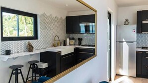 Une cuisine moderne avec des meubles noirs, un plan de travail blanc et un grand miroir.