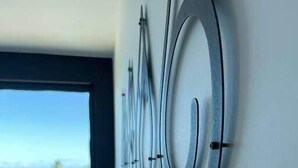 Une chambre à coucher moderne avec une grande fenêtre, un lit et une œuvre d’art abstraite accrochée au mur.