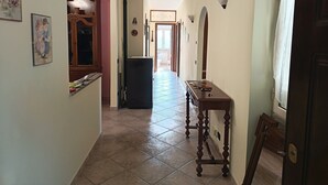 Un couloir avec un sol carrelé, une table en bois et une porte sur la droite.