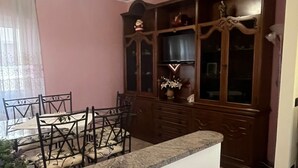 Un coin repas avec une table et des chaises, un buffet en bois doté de portes en verre et un luminaire suspendu au plafond.