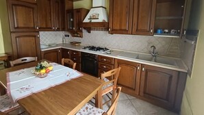 Une cuisine avec des meubles de rangement en bois, une cuisinière à gaz, un évier et une table à manger avec des chaises.