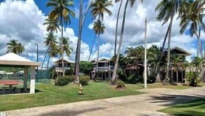 Un resort con varias edificaciones, palmeras y un paseo techado.