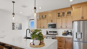 A modern kitchen with wooden cabinets, stainless steel appliances, and a central island with seating. - Lake and Lift Lodge at Gondola Crossing (Heber City)