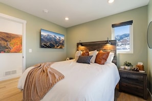 A bedroom with a bed, a nightstand, a window with a view, and two wall-mounted pictures. - Lake and Lift Lodge at Gondola Crossing (Heber City)